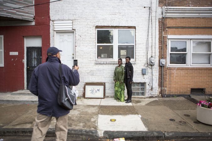 Bill Chaney, left, snaps a photo on his phone of Diane Precht, right, and her mother Daisy, center, in front of their former home on East Williams Street in Jewtown. (Photo by Jessica Kourkounis)