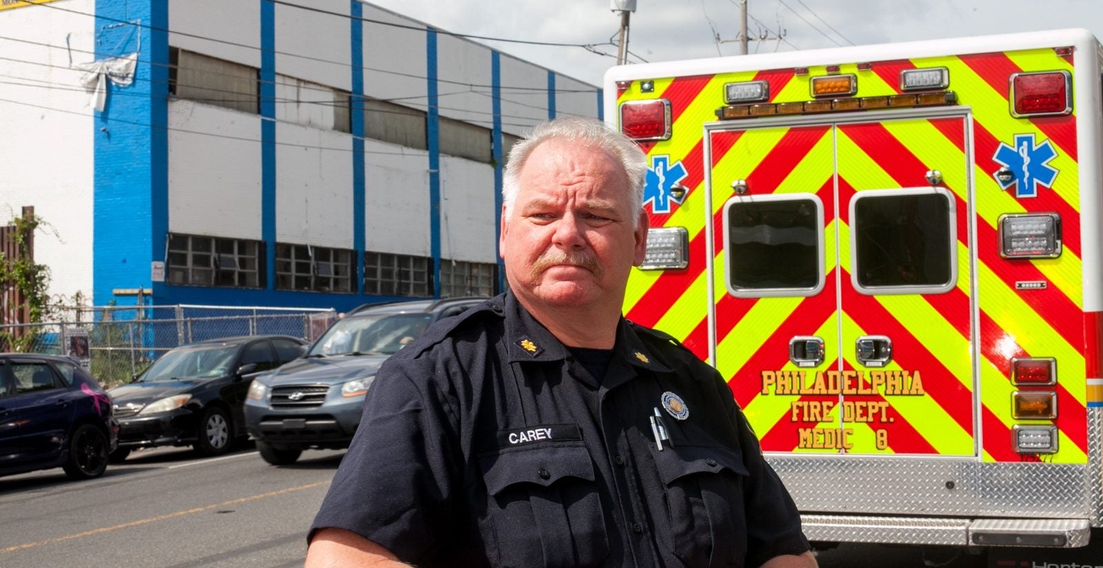 Kevin Carey, a fire paramedic chief with the Philadelphia Fire Department stands near an ambulance after responding to a call for a cardiac arrest in the Kensington section of Philadelphia. (Brad Larrison for WHYY)