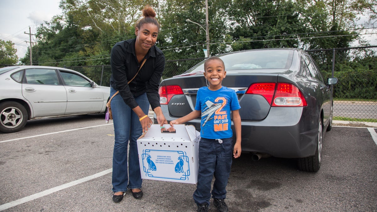 Kiera Fletcher, of Levittown, poses with her son Devante, 3, and the box that holds their new kitten. (Emily Cohen for WHYY)