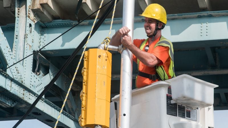 The Streets and Traffic team works above and on the ground to repair a signal. (Branden Eastwood for WHYY)