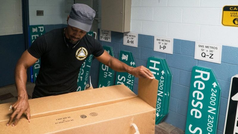 A Traffic Signal and Sign Shop employee works next to an assortment ready for use. (Branden Eastwood for WHYY)