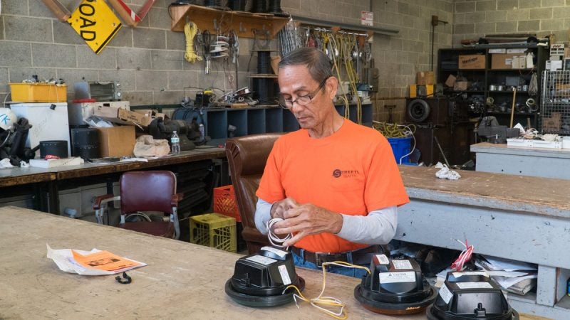 A Traffic Signal and Sign Shop staffer works with lamp parts. (Branden Eastwood for WHYY)