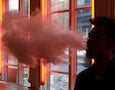 a man exhales vapor from an e-cigarette