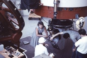 Vera Rubin at Lowell Observatory in 1965. Kent Ford, her longtime collaborator is kneeling in the hard hat. (Photo by Bob Rubin)