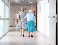 two women walk down a hospital hallway