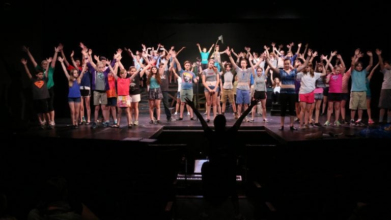 The cast of 'Children of Eden' raise their hands during a rehearsal at Wolf Performing Arts Center in Wynnewood. (Peter Crimmins/WHYY)