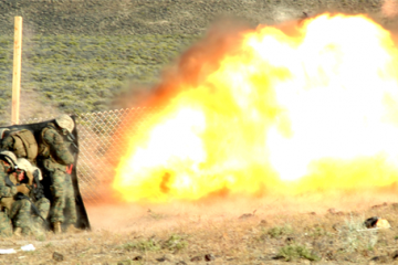  Marines from Combat Engineer Platoon, Marine Wing Support Squadron 473 blow a hole in a fence at Hawthorne Army Weapons Depot in Nevada on June 17, 2010 during demolitions training for exercise Javelin Thrust 2010. The Marines used a kevlar blanket to shield themselves from fragmentation and to reduce the impact of the blast. (Photo by Pfc. Nana Dannsaappiah) 