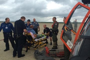  An MH-65 Dolphin helicopter crew from Air Station Atlantic City, N.J., transfers a man to local emergency medical services personnel, at the air station, July 15, 2014. The aircrew medevaced the man from a fishing boat about 45 miles off shore from Ocean City, Maryland, after the man experienced health issues. (U.S. Coast Guard photo) 