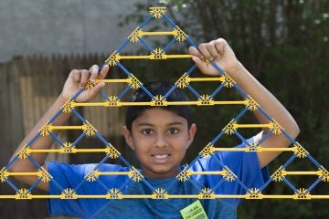 Anjay Bhatt shows off a Sierpinski Triangle created  with K'NEX. His triangle was a piece of the larger 45 by 90 foot triangle built in  yard of the Wagner Free Institute of Science. (Jonathan Wilson For Newsworks)