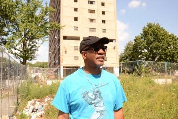  The windows to the second-floor apartment Neil Blunt grew up in can be seen behind him. (Jimmy Viola/for NewsWorks) 