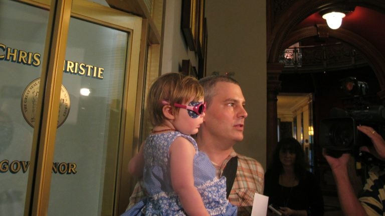  Brian Wilson, of Scotch Plains, N.J. holds his 2-year-old daughter Vivian as they prepare to deliver boxes of letters to Gov. Chris Christie's office in Trenton, N.J., on Thursday, Aug. 1, 2013. (Geoff Mulvihill/AP Photo) 