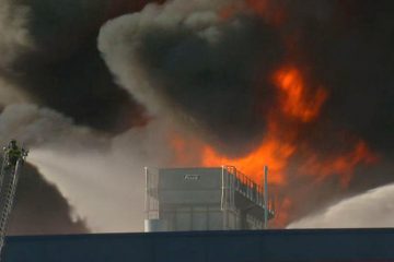 20130903-dietzandwatsondeliwarehousefireroofflame1200 Firefighter battles flames billowing into the sky at the Dietz & Watson deli meat storage facility in Delanco, Burlington County, N.J. (Photo by NBC10)