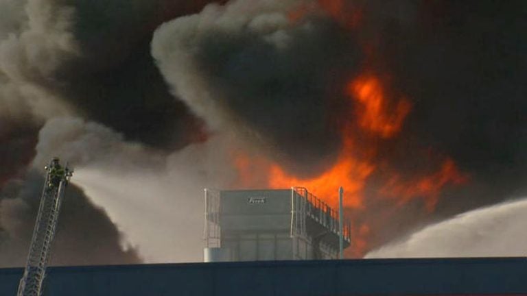  Firefighter battles flames billowing into the sky at the Dietz & Watson deli meat storage facility in Delanco, Burlington County, N.J. (Photo by NBC10) 