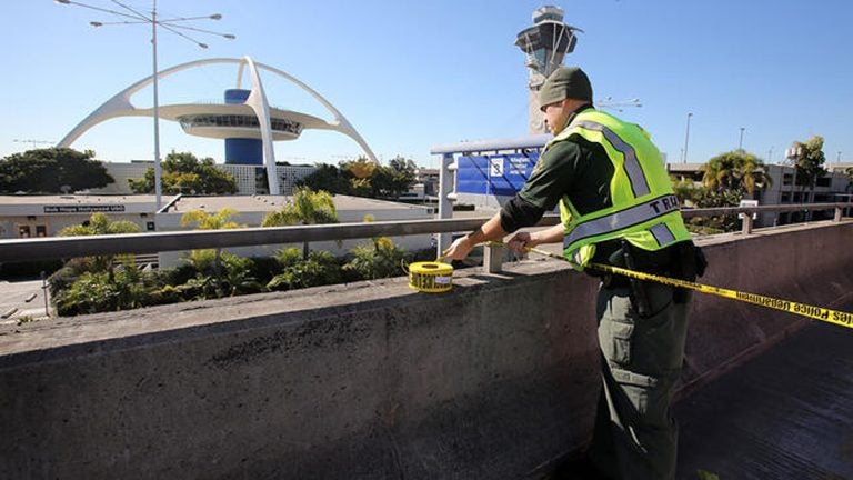 20131101-lax-gunman-generic-1200 A police officer closes a road at the Los Angeles International Airport on Friday Nov. 1, 2013, after shots were reporter in Terminal 3, prompting authorities to evacuate the terminal and stop flights headed for the city from taking off from other airports. (AP Photo/Ringo H.W. Chiu)