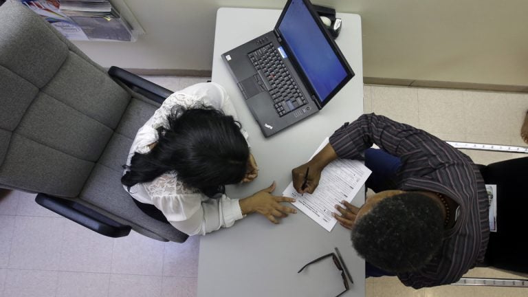 At a health center in Trenton, Rachael Richardson, (left), helps Louis Peters to sign-up for a new health insurance plan (Mel Evans/AP Photo) 