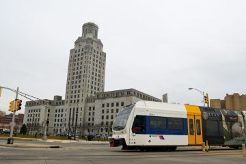 An NJ Transit Riverline train passes in front of City Hall in Camden