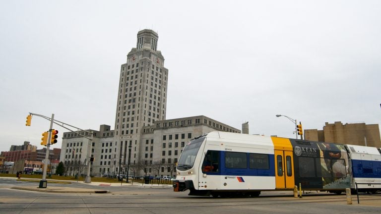 An NJ Transit Riverline train passes in front of City Hall in Camden