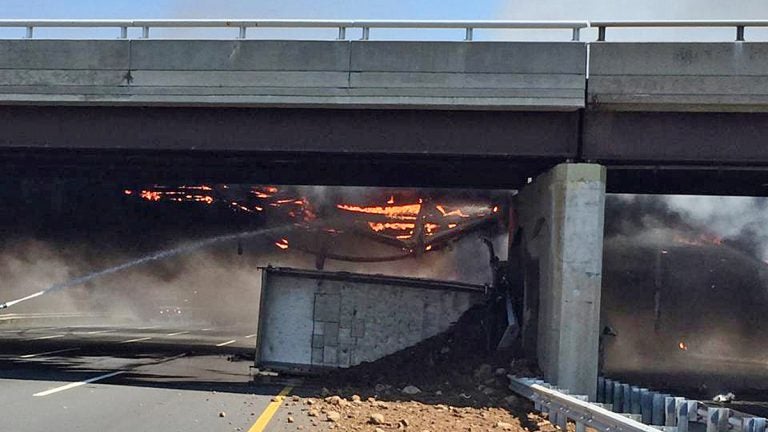  In this photo taken Tuesday, Aug. 4, 2015, and provided by the New Jersey State Police, a fire burns around a dump truck after it hit the South Wood Avenue overpass and overturned in Linden, N.J. (AP Photo/Sgt. Jeremy Micewicz, New Jersey State Police via AP) 