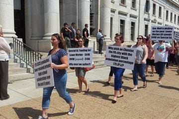  Parents and teachers march with their messages in front of the Chester County Courthouse Monday. (Laura Benshoff/WHYY) 