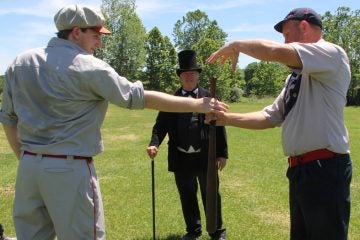 Danny Shaw (left) of the Flemington Neshanock and Erik Meyers of the Elkton Eclipse determine which team bats first under the supervision of umpire Sam Bernstein. (Emma Lee/WHYY)