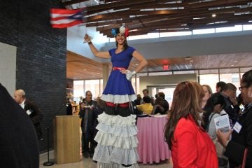 Stilt walker Samantha Hyman waves a Puerto Rican flag above the crowd at the grand opening of Taller Puertorriqueño's new cultural center. (Emma Lee/WHYY)