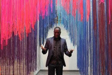 Architect Francis Kéré beckons visitors into into an installation that represents both Philadelphia and his home village of Gando in Burkina Faso. Hanging paracute cords create enclosures and recorded sounds from both locations play softly. (Emma Lee/WHYY)