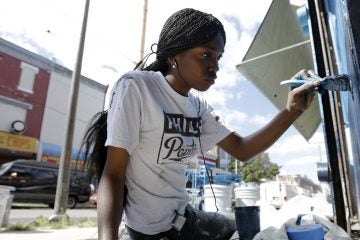 Natalie Glover paints a store front on a commercial corridor in North Philadelphia as part of the city’s renowned Mural Arts Program. Liz Dow names Mural Arts Executive Director, Jane Golden as a “spark” that inspires others. (AP Photo/Matt Rourke) 