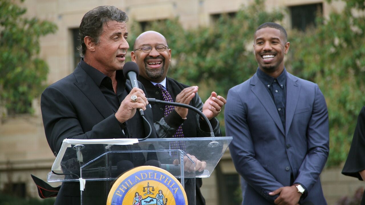  Sylvester Stallone speaks to a crowd at the top of the Art Museum steps about his new film, 'Creed.' Joining him ar Philadelphia Mayor Michael Nutter, center, and Michael B. Jordan, who portrays Adonis Creed in the movie opening Thanksgiving weekend. (Emma Lee/WHYY)  