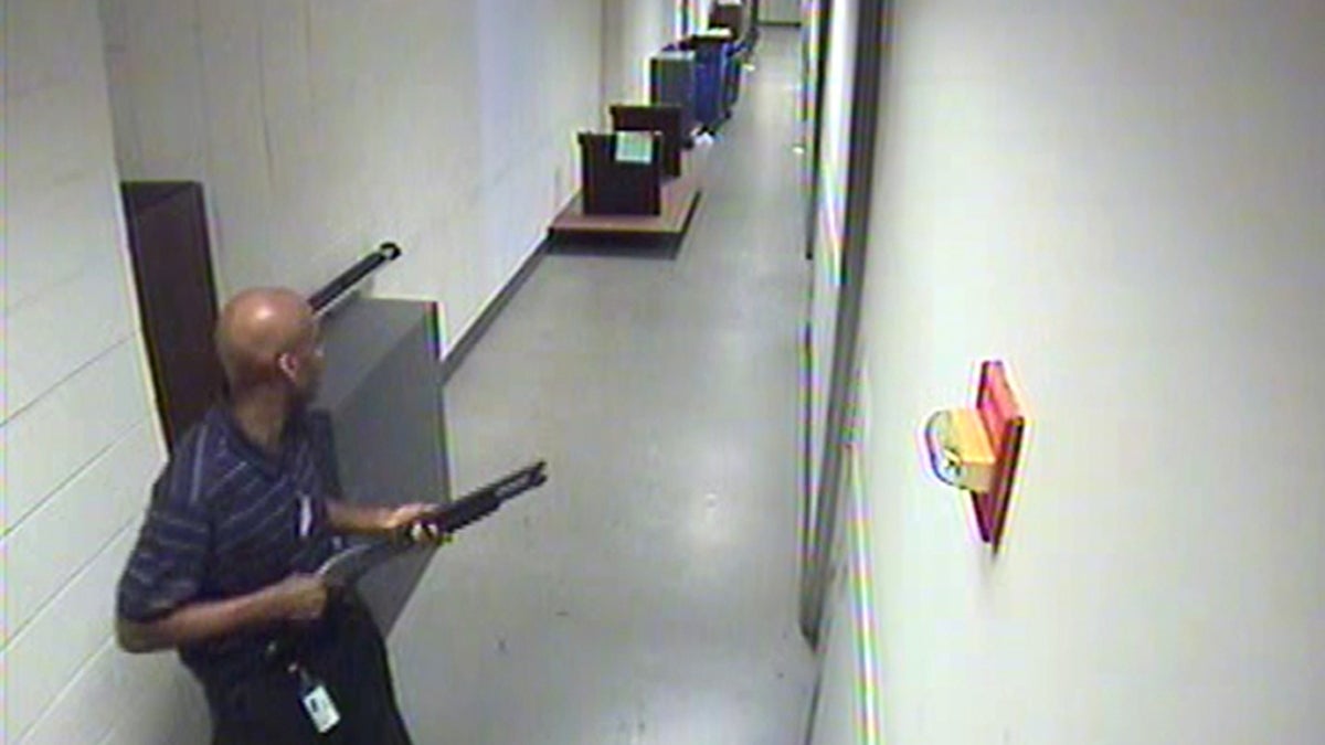  This image from video provided by the FBI, shows Aaron Alexis carrying a Remington 870 shotgun inside a Navy Yard building, where he shot and killed 12 people on Monday, Sept. 16. (AP Photo/FBI) 