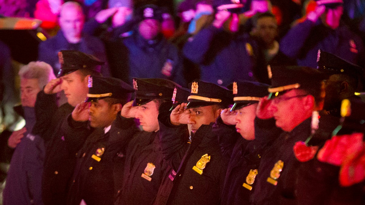  Mourners stand at attention as the bodies of two fallen NYPD police officers are transported from Woodhull Medical Center on Saturday. (AP Photo/John Minchillo) 
