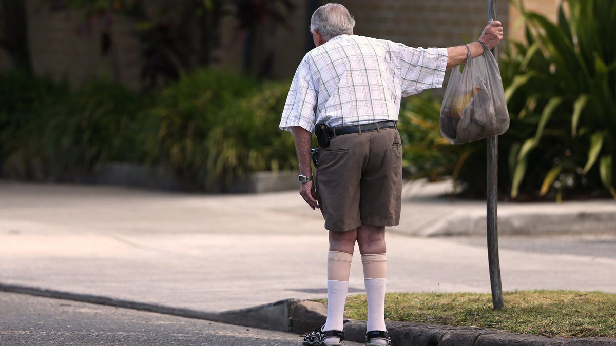  An elderly man holds onto a signpost on the side of a road.  (AP Photo/Rick Rycroft, File) 