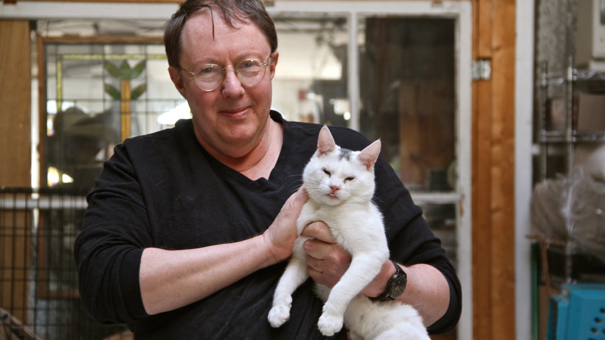 Al Gury holds Marley, one of the hundreds of cats he has fostered in his Old City home. (Emma Lee/WHYY)