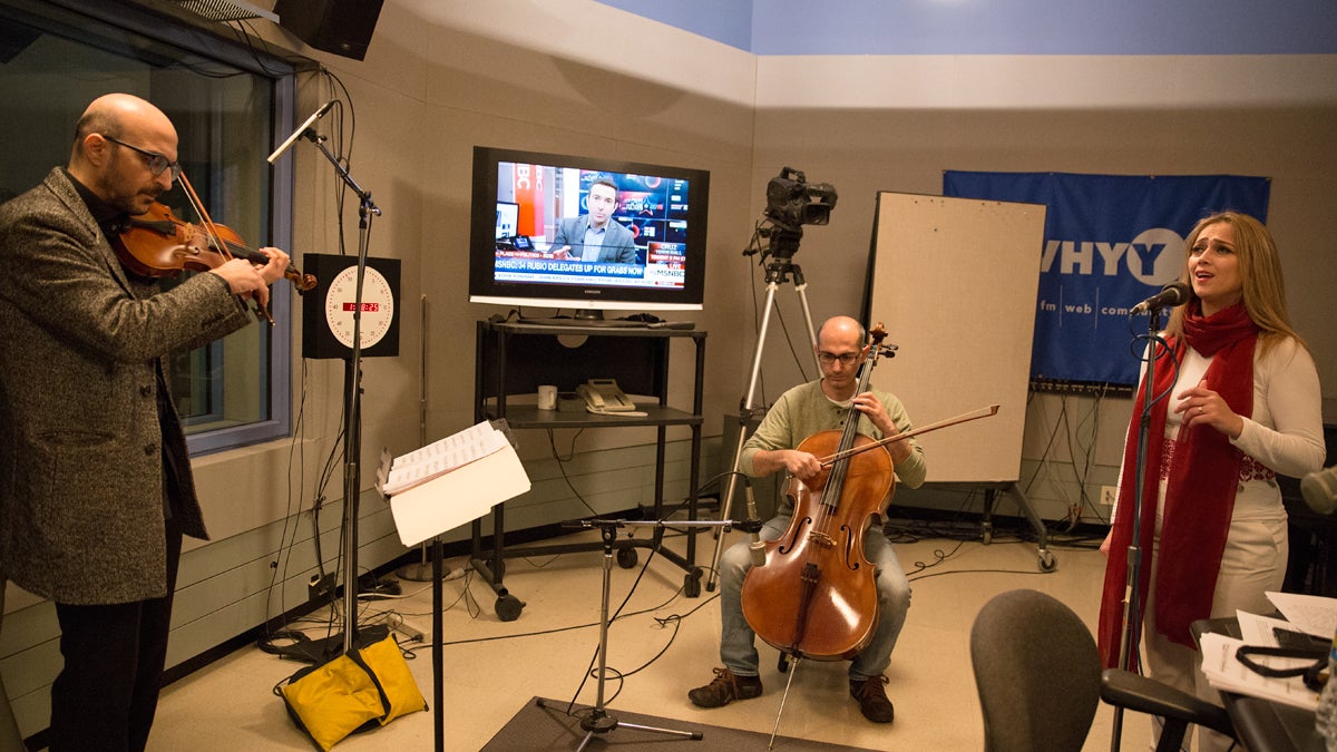 Guest singer Dalal Abu Amneh (right) performs with music director and violinist Hanna Khoury (left) and cellist Kinan Abou-afach of the Al-Bustan Takht Ensemble at WHYY Studios.  (Lindsay Lazarski/WHYY) 