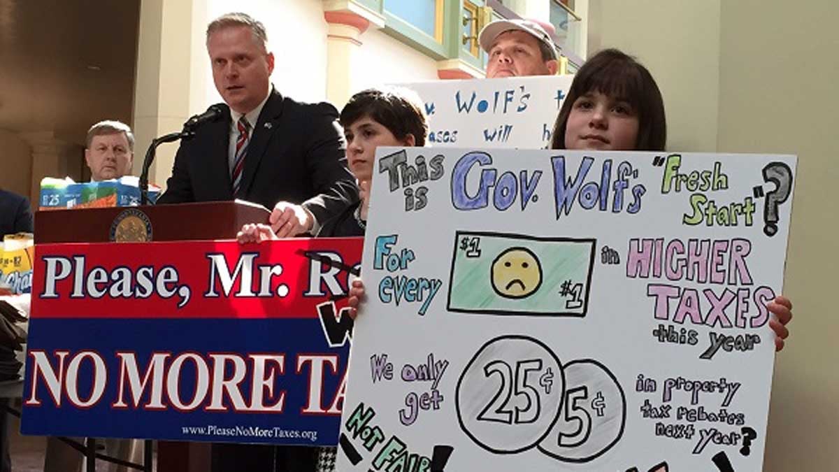  Lebanon County residents L.J. Brouillette, 10, and Samantha Brouillette, 8, hold signs as Pennsylvania Rep. Fred Keller, R-Union, speaks against the proposed sales and income tax increases in the Wolf budget plan. (Mary Wilson/WHYY) 