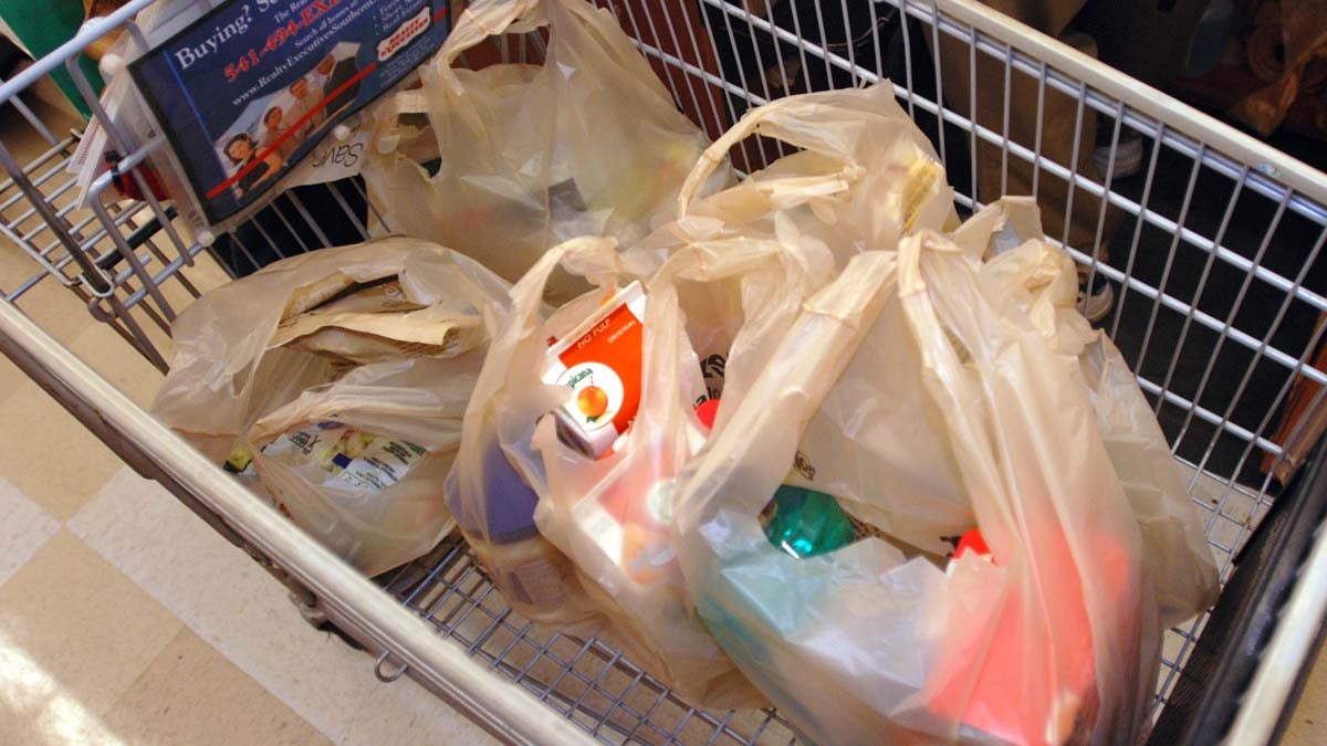 Groceries in plastic bags inside a shopping cart.