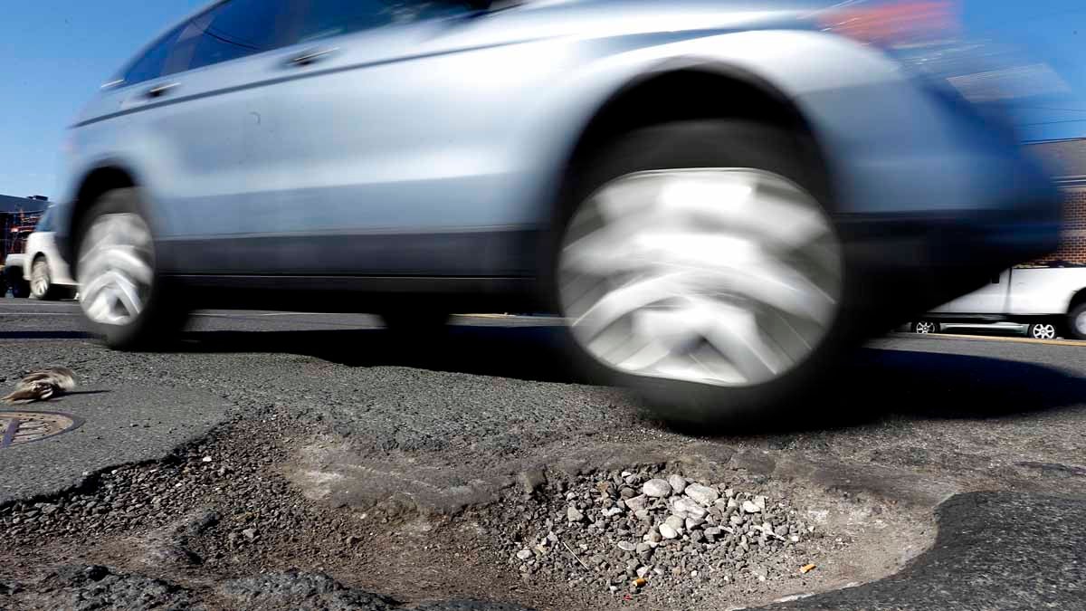  A car barely misses a pothole in Philadelphia. Since December, PennDOT has used more than 50,000 tons of patching material to fill the craters throughout the region. (AP file photo) 