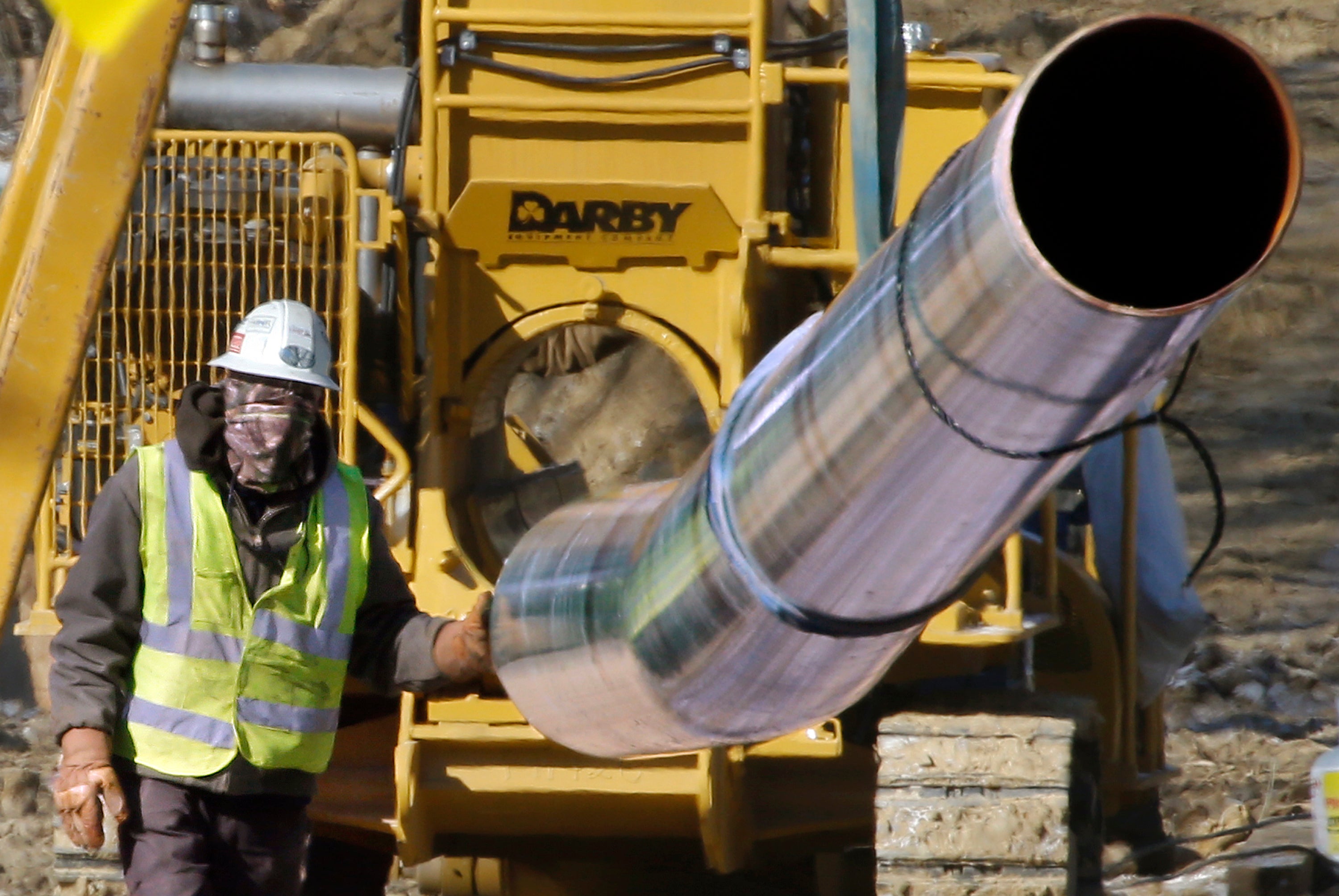 A worker guides a section of pipe while working on a shale gas pipe line Friday