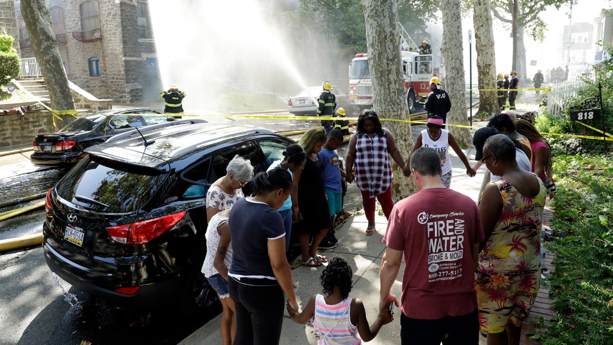 People pray as firefighters battle a blaze at a Presbyterian church in the Overbrook neighborhood of Philadelphia