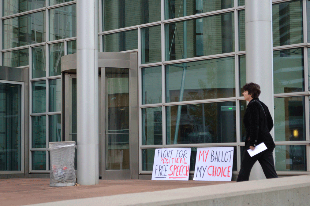 A woman enters the Alfred A. Arraj Courthouse past signs placed by those protesting against the ban to take selfie photos by voters showing a completed ballot