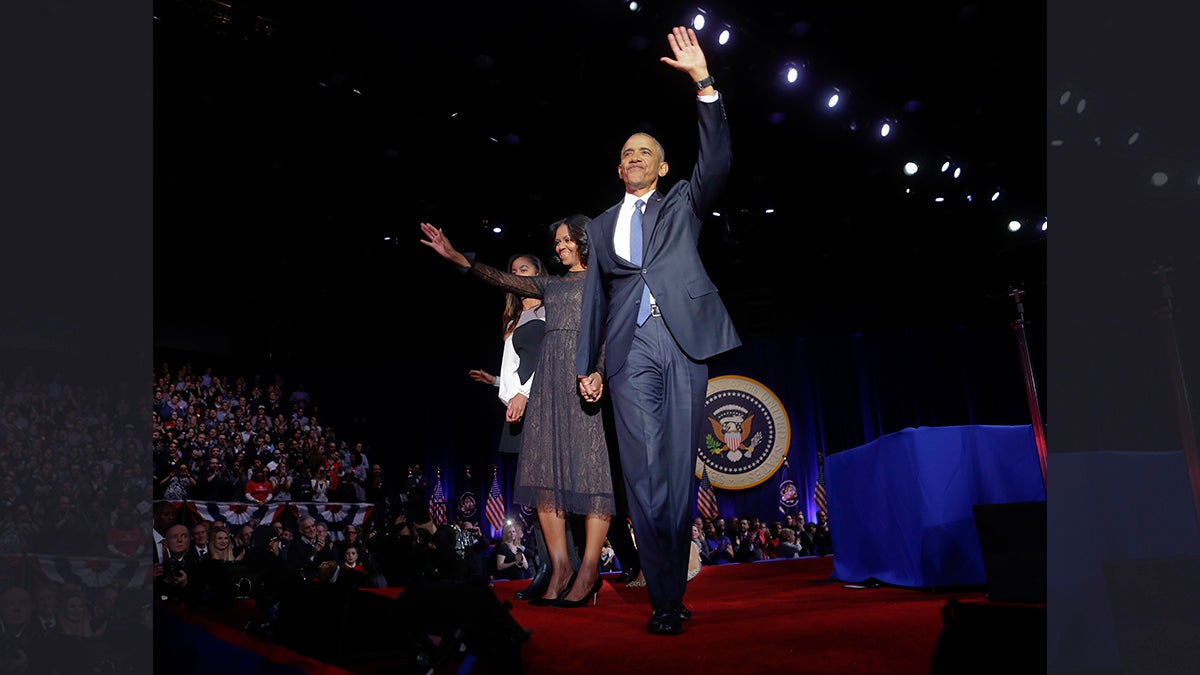 President Barack Obama waves on stage with first lady Michelle Obama