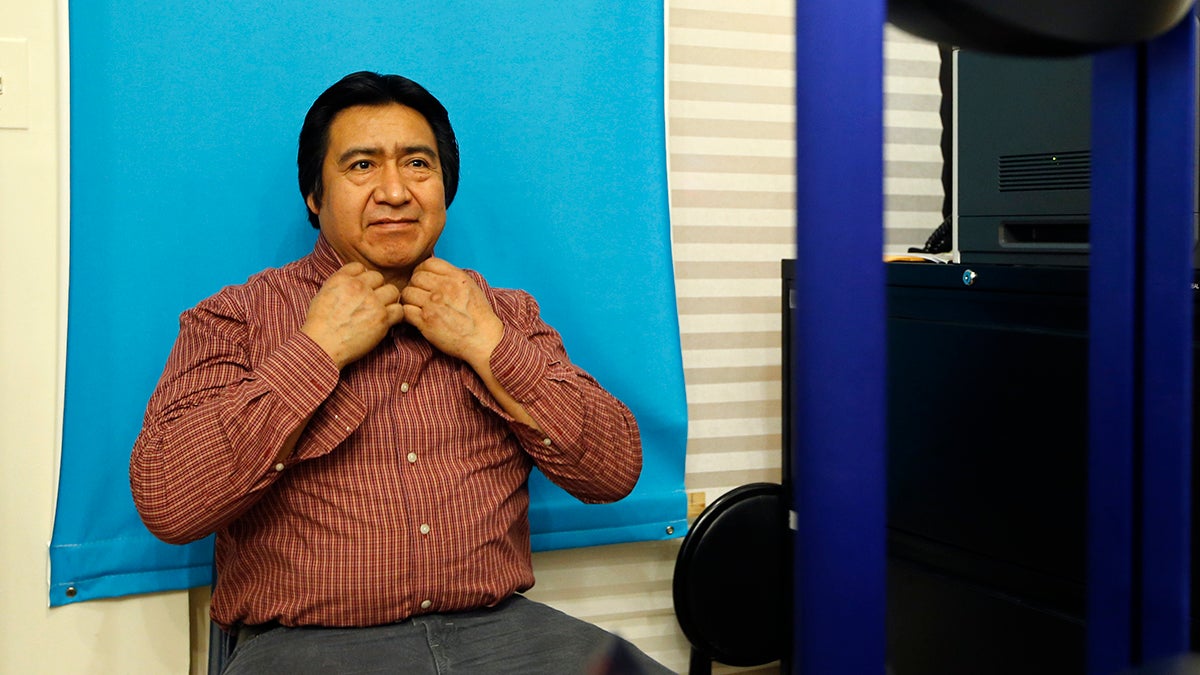  Luis Gordillo, a carpenter from Ecuador, adjusts his shirt collar as he has his picture taken while applying for a New York City municipal ID card. (AP Photo/Kathy Willens) 