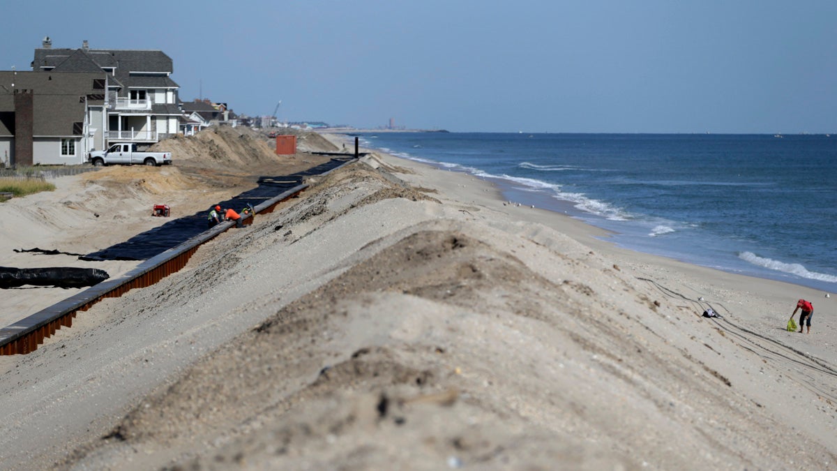  A woman, right, scavenges on the beach while workers labor on the new seawall construction project to protect Mantoloking, New Jersey, from the Atlantic Ocean. As the third anniversary of Superstorm Sandy approaches, New Jersey says it has acquired 90 percent of the easements it needs to do shore protection work along the coast. New Jersey is beginning to exercise its power of eminent domain to secure other easements. (AP file photo) 