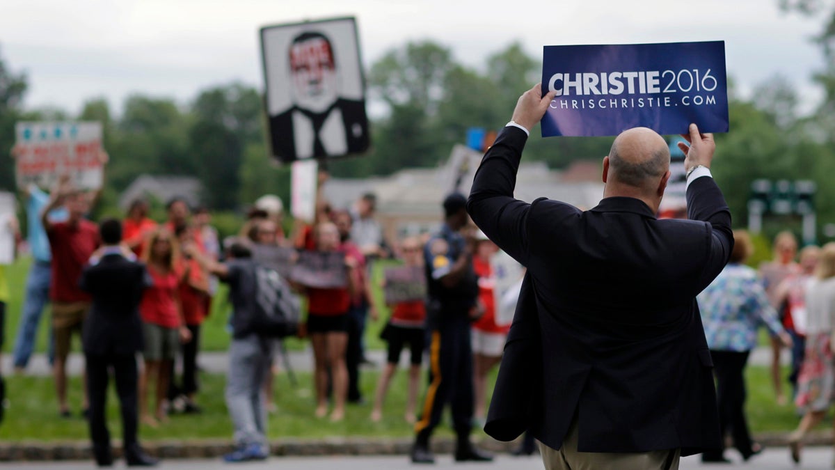  A man holds up a Christie for president sign as he passes a group of protesters after Christie announced that he is running for the Republican nomination for president Tuesday at Livingston High School in Livingston, New Jersey. (AP Photo/Mel Evans) 