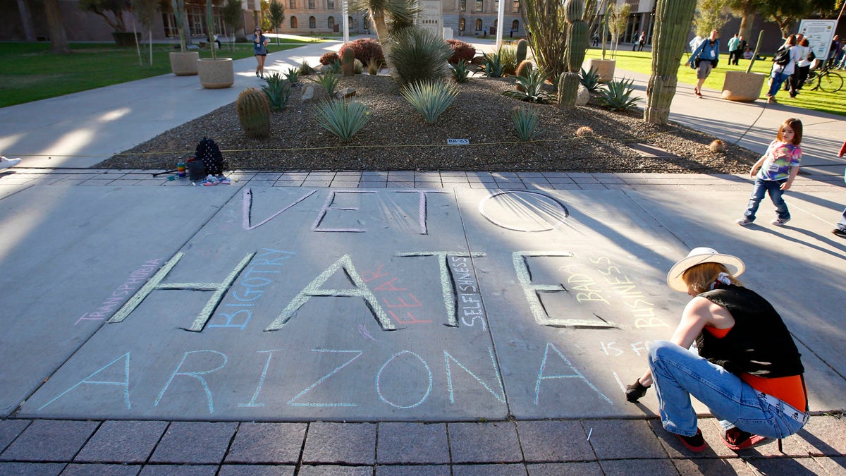  Margaret Jean Plews works on a chalk drawing as she joined nearly 250 gay rights supporters protesting SB1062 at the Arizona Capitol, Friday, Feb. 21, 2014, in Phoenix. The protesters gathered demanding Gov. Jan Brewer veto legislation that would allow business owners to refuse to serve gays by citing their religious beliefs. The governor must sign or veto Senate Bill 1062 by the end of next week. (Ross D. Franklin/AP Photo) 