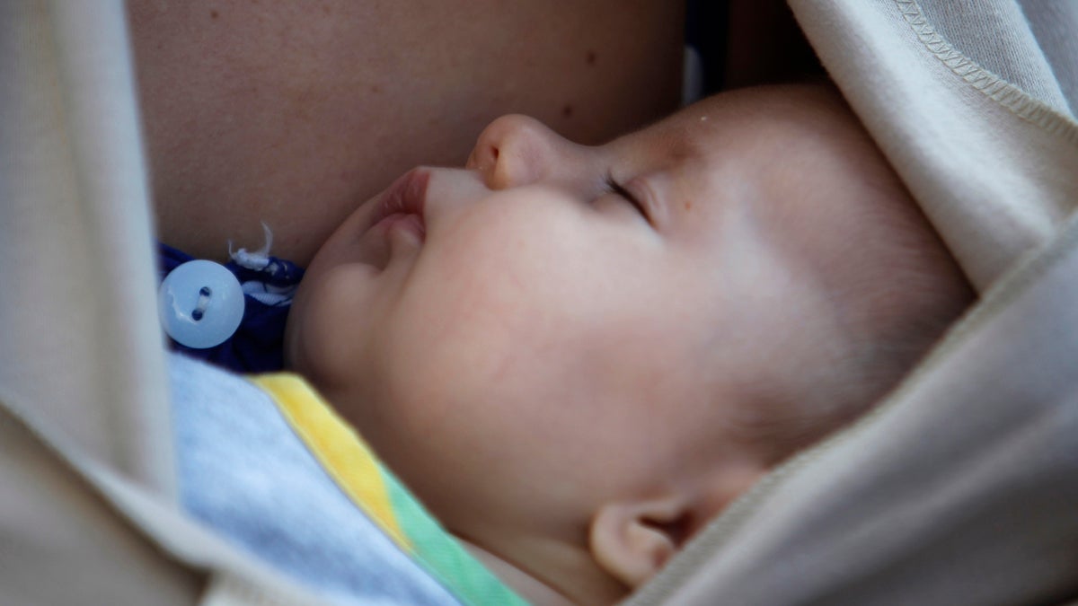  A baby sleeps in the arms of his mother after a mass breastfeeding in celebration (Nikolas Giakoumidis/AP Photo) 