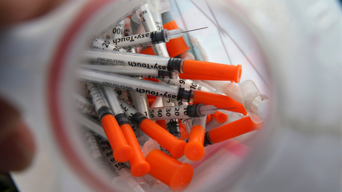  A jug of used needles sits near  an industrial area of Camden. (Mel Evans/AP Photo) 