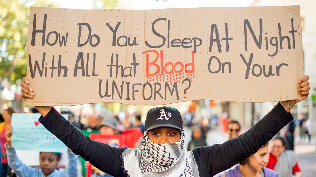 A woman, who declined to give her name, joins several hundred others in Oakland, Calif. on Wednesday, Aug. 20, 2014 during a protest against the shooting of Michael Brown, an unarmed black 18-year old by a white police officer in Ferguson, Mo. (AP Photo/Noah Berger)