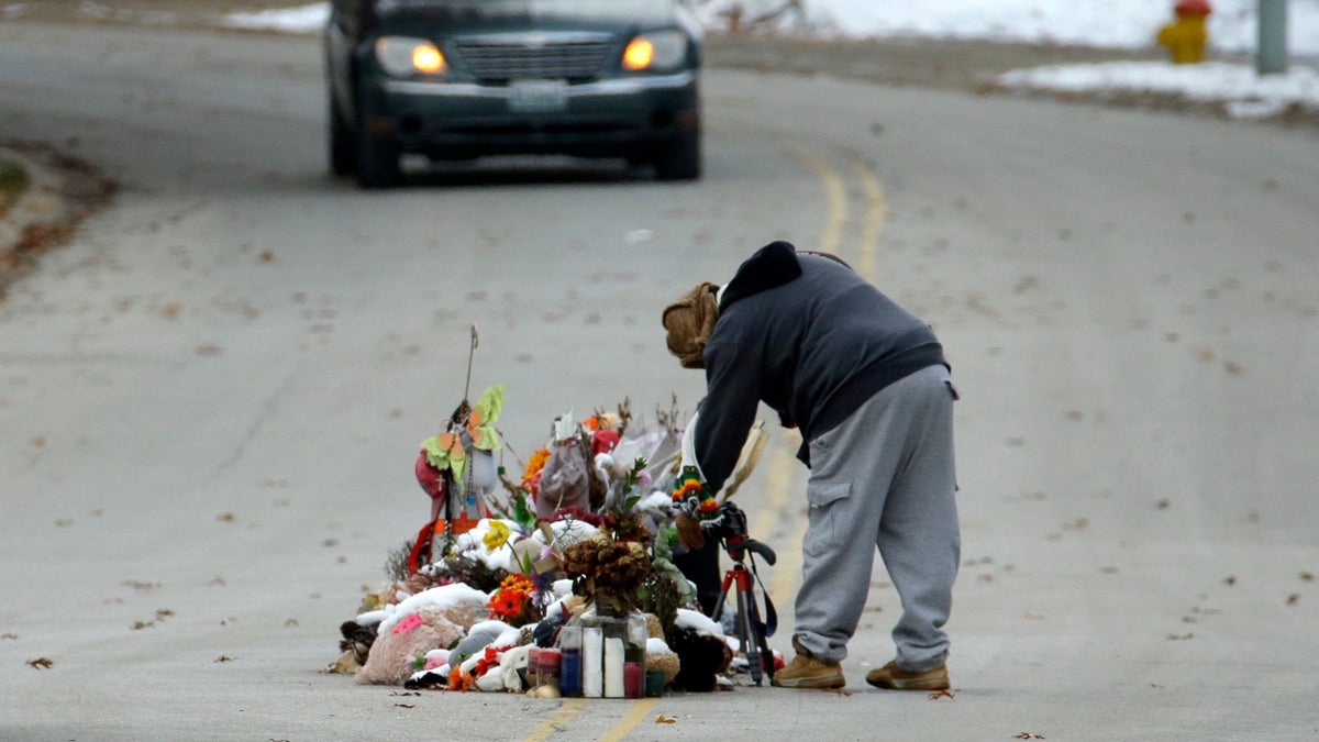 A woman looks at a memorial in the middle of the street Monday