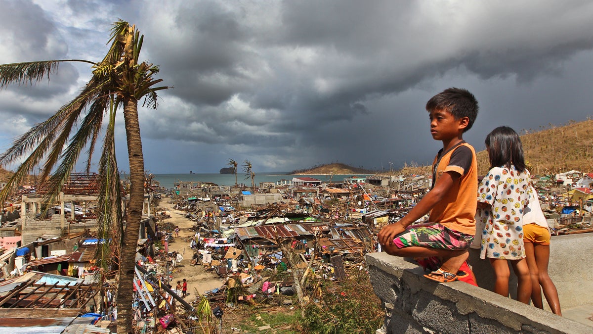  Filipino children play as houses damaged by Typhoon Haiyan are seen in the background in Marabut, Philippines, Thursday, Nov. 14, 2013. (Dita Alangkara/AP Photo, file) 
