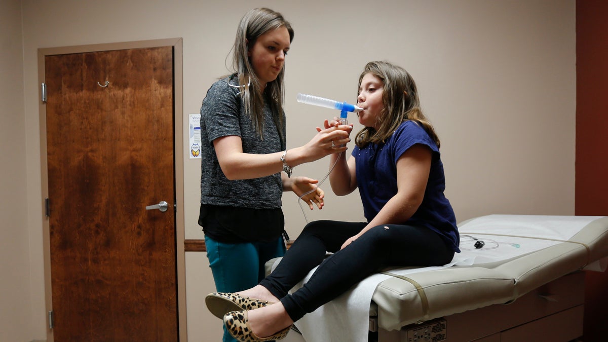  A physician assistant administers a nebulizer treatment to a patient. (Mike Groll/AP Photo) 